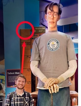 Chris Ulery standing beside a life-size model of Robert Wadlow, the tallest man on record at 8 feet 11 inches